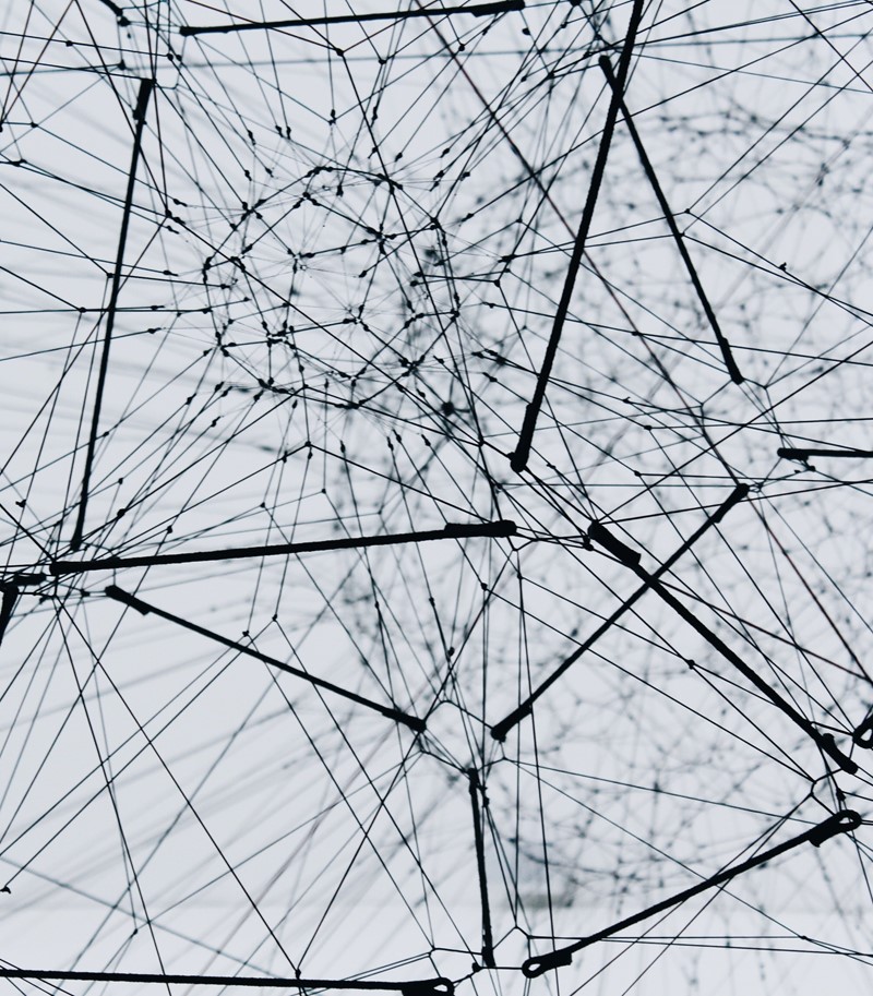 Black and white photograph of a complex web made of medal wires come in and out of various central nodes