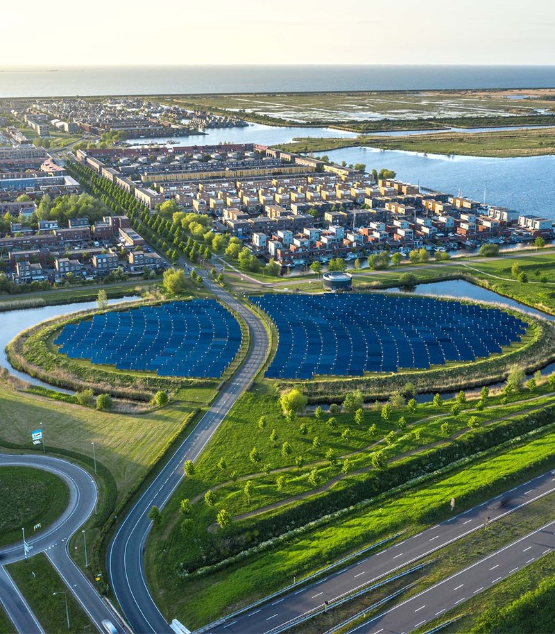 Aerial shot of a field of solar panels powering an adjacent neighbourhood in the Netherlands.