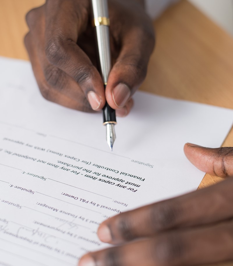 Male hand holding a fountain pen signing a document